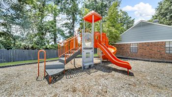A playground with a red slide and a white platform.